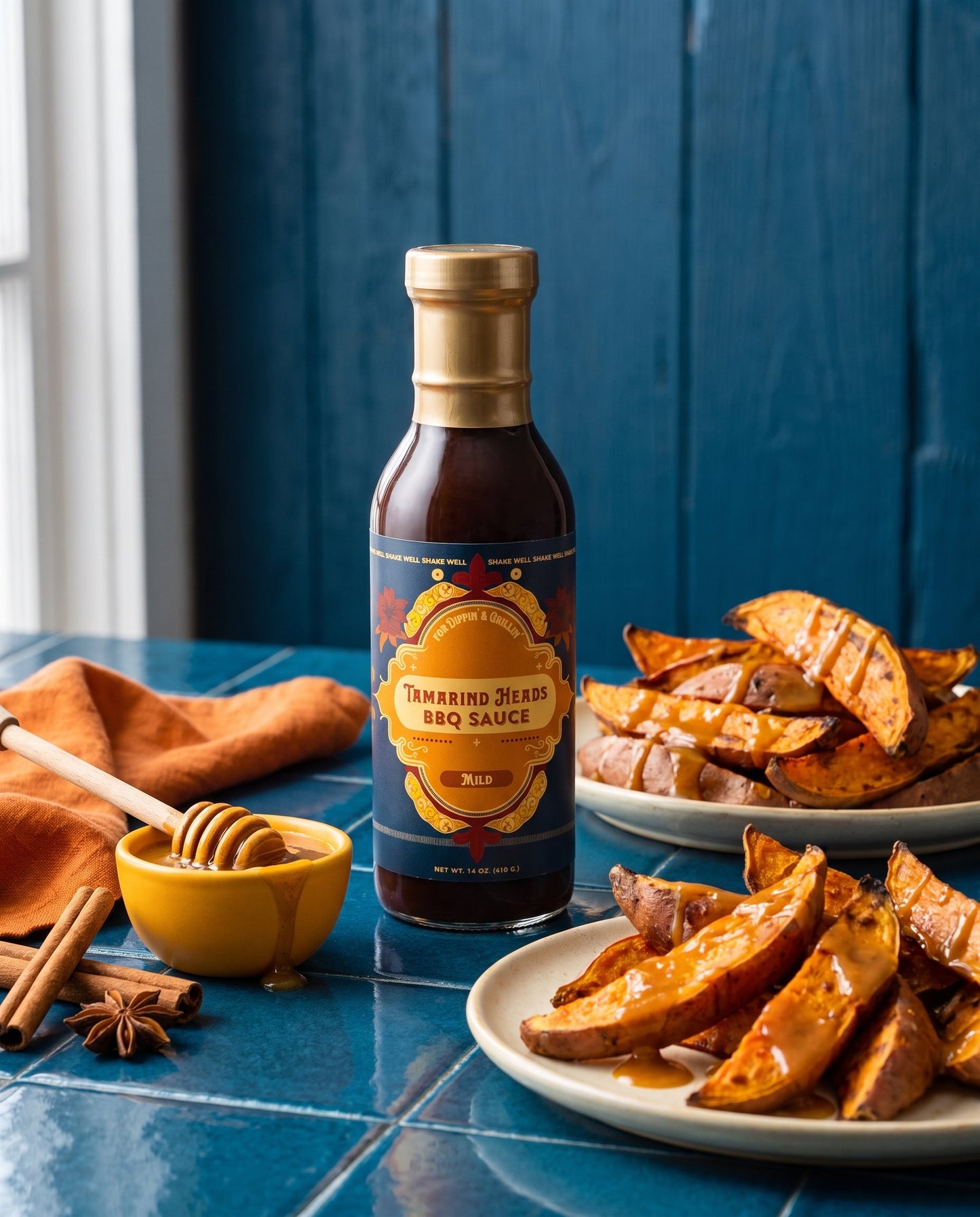 Tamarind Heads Spiced Honey Mild BBQ sauce bottle with roasted sweet potato wedges, honey and cinnamon