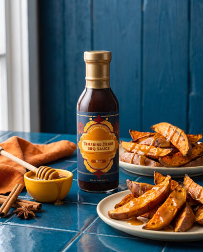 Tamarind Heads Spiced Honey Mild BBQ sauce bottle with roasted sweet potato wedges, honey and cinnamon